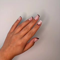 Hand with pink brown french tip press on nails on a plain background