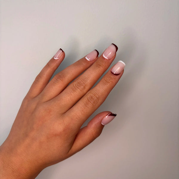 Hand with pink brown french tip press on nails on a plain background