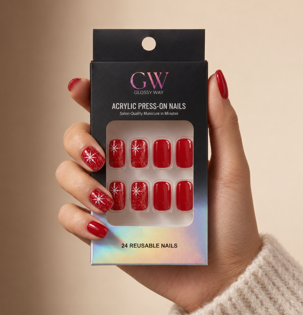 A hand wearing glossy red press-on nails with white starburst designs holds a black retail box labeled GW Glossy Way Acrylic Press-On Nails. The box has a holographic lower edge and shows 8 sample nails in the window packaging.