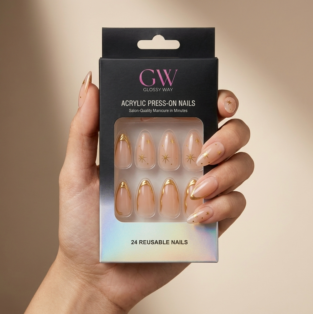 A hand holding a black box of Glossy Way (GW) acrylic press-on nails. The nails shown through the clear window are nude beige with gold star and crescent moon designs, and the hand itself has matching nude nails with gold accents.