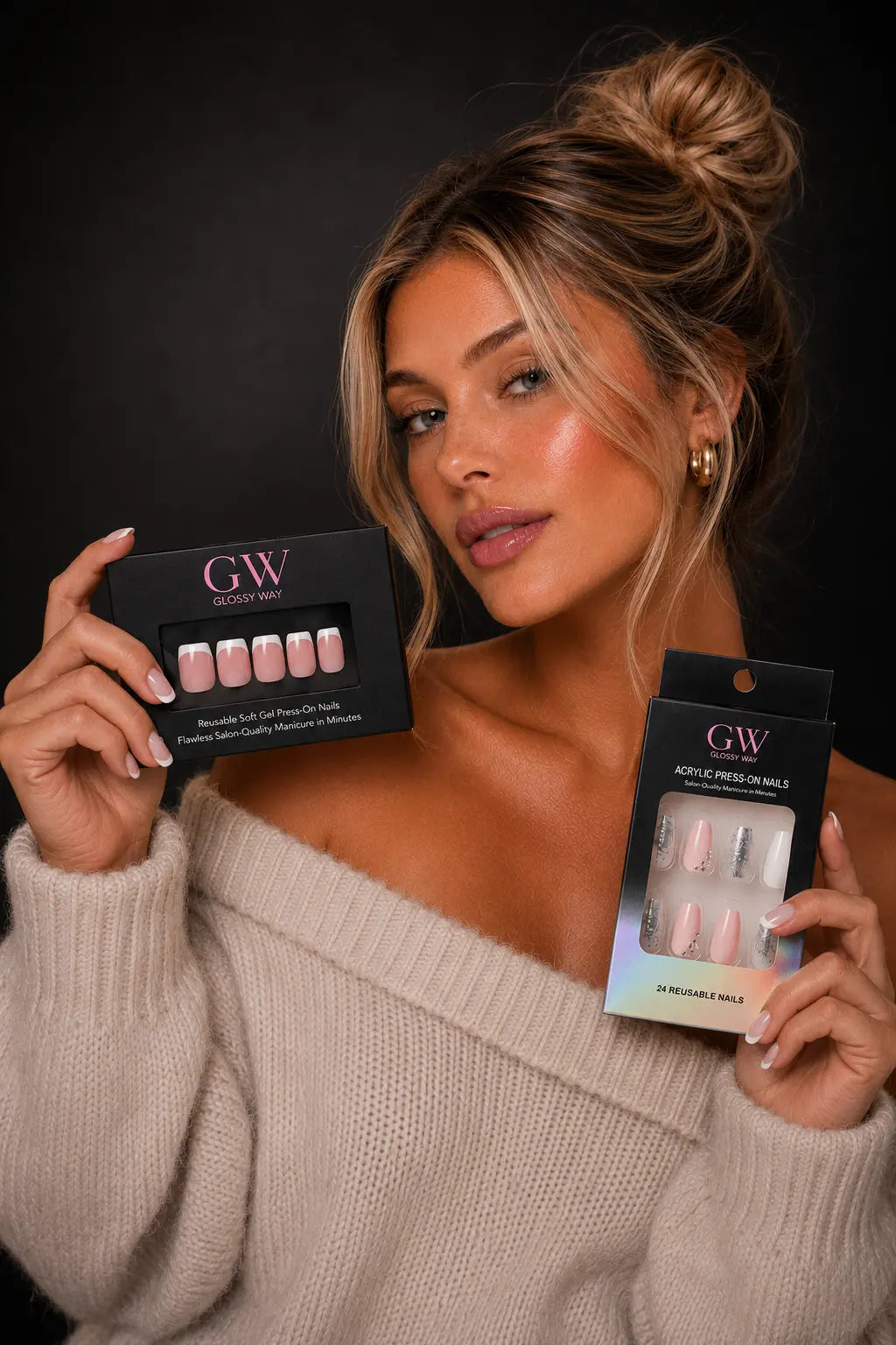 A woman in a beige knit sweater holds two black boxes of GW Glazed Nail press-on nails with pale pink and nude shades against a dark studio background.