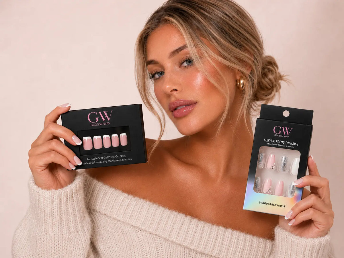 A woman holds two black GW Press On Nails boxes in both hands against a soft beige background. The left box shows pink press-on nails, and the right box shows a mix of pink, nude, and silver press-on nails.