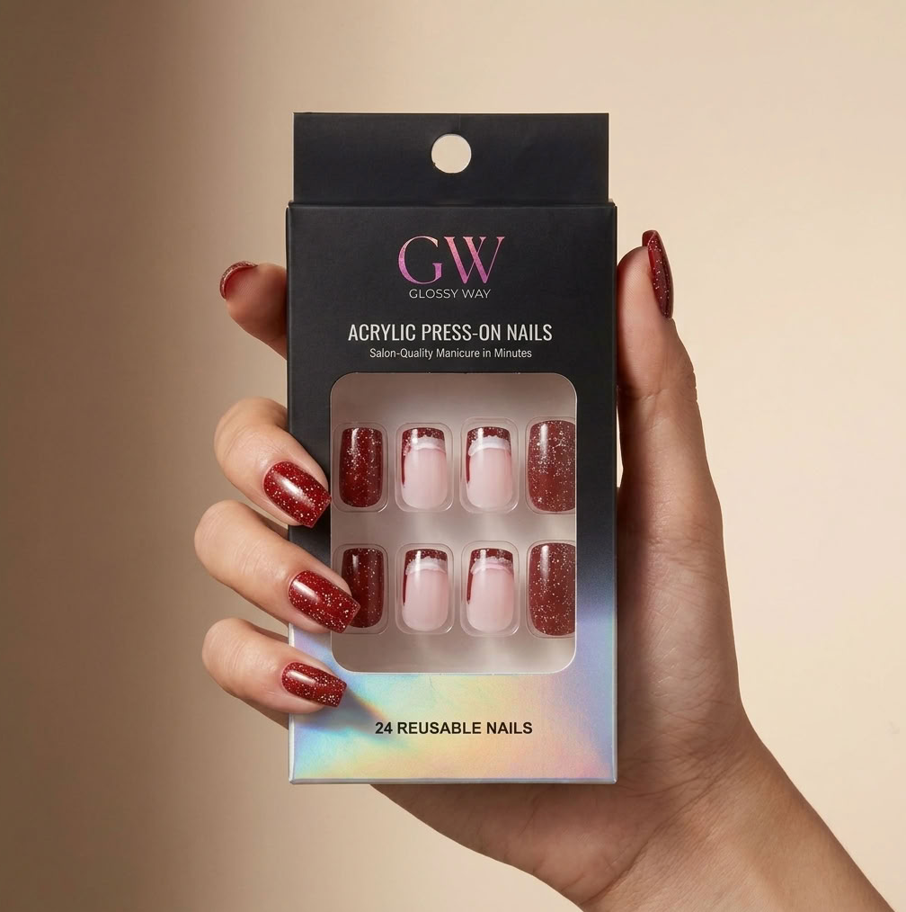 A hand holding a black glossy way brand box of press-on acrylic nails. The nails inside are shown in three styles: a deep glittery red, a sheer pink with a glittery red tip, and a solid light pink.